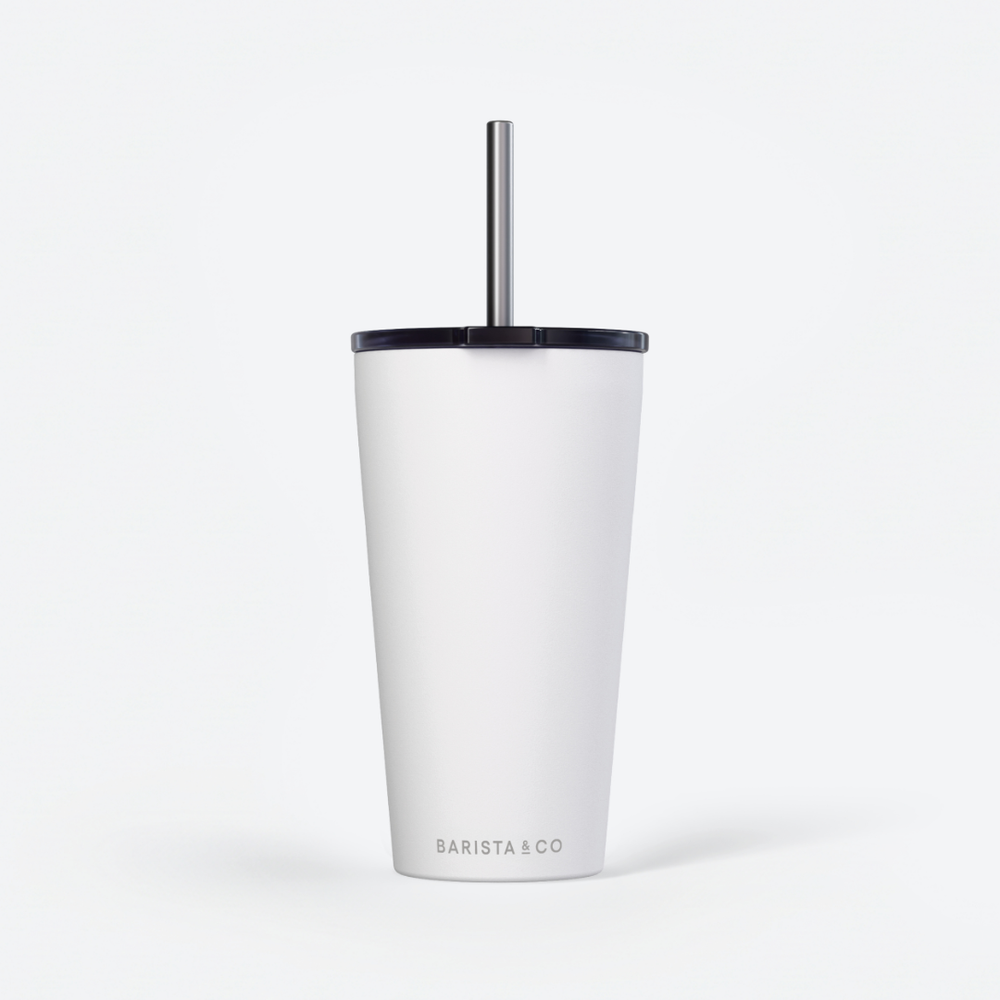 A white insulated travel tumbler with a black lid and a silver metal straw, featuring the BARISTA & CO logo near the bottom, set against a clean white background.
