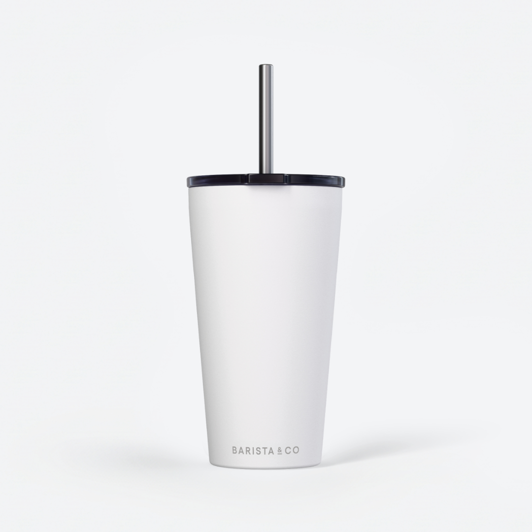 A white insulated travel tumbler with a black lid and a silver metal straw, featuring the BARISTA & CO logo near the bottom, set against a clean white background.
