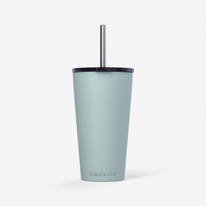 A matte light blue insulated travel tumbler with a black lid and a silver metal straw, featuring the 'BARISTA & CO' logo near the bottom, set against a clean white background.