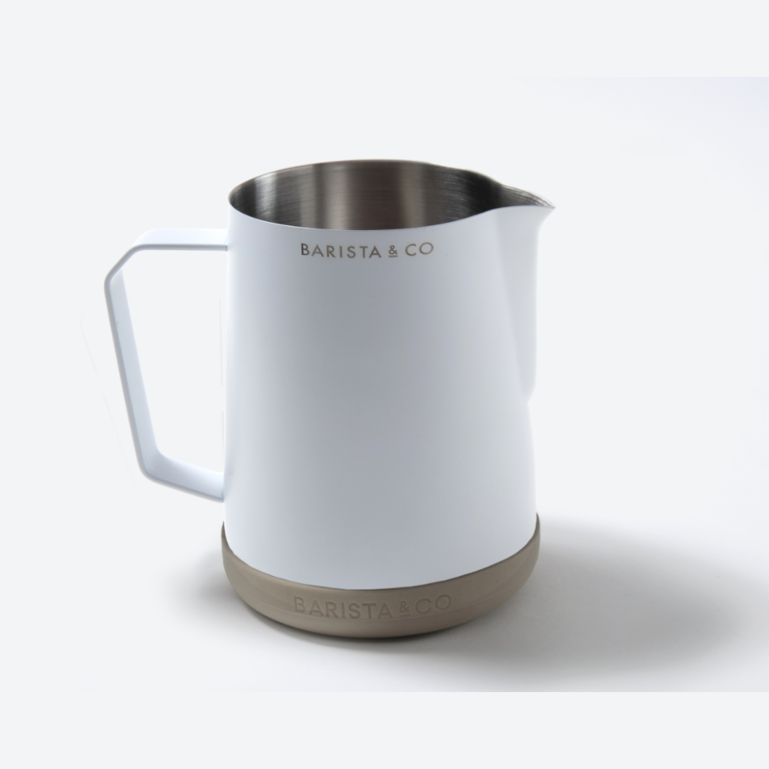 A white Barista & Co milk pitcher with a stainless steel interior and a beige textured base, shown on a clean white background.
