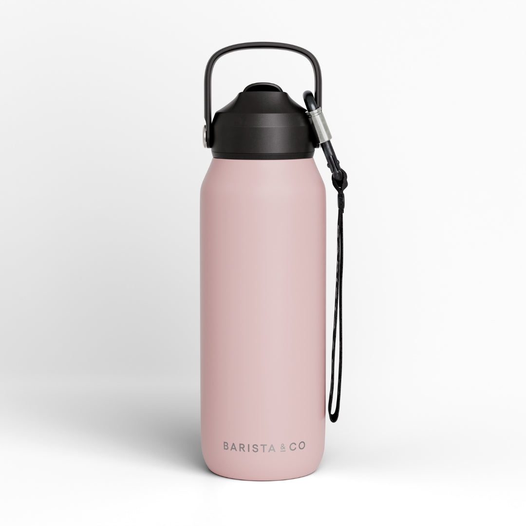 A pink insulated water bottle with a black lid, carrying loop, and black wrist strap, shown on a clean white background. The brand name 'BARISTA CO' is printed near the bottom.