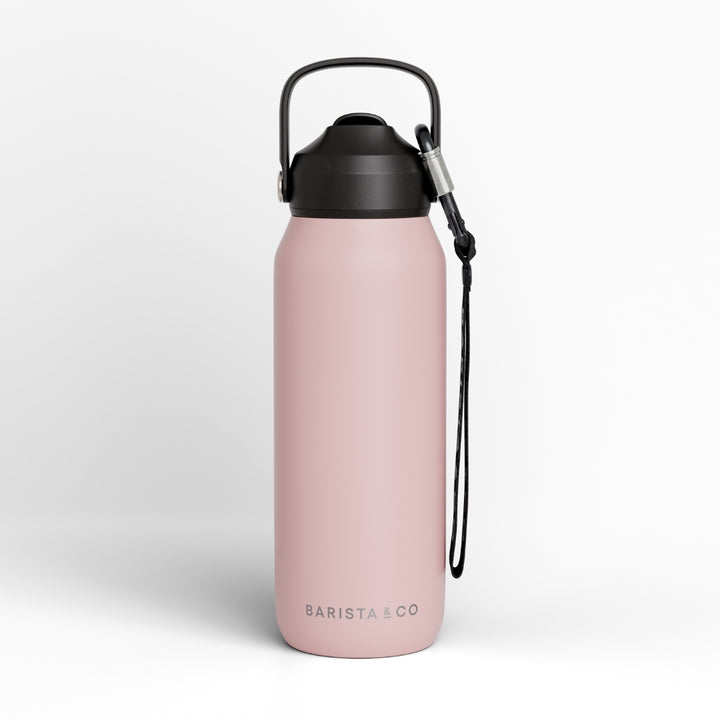 A pink insulated water bottle with a black lid, carrying loop, and black wrist strap, shown on a clean white background. The brand name 'BARISTA CO' is printed near the bottom.